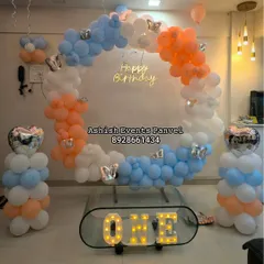 A modern and elegant ring backdrop for a first birthday. The pastel blue, orange, and white balloons, accented with butterfly details and a neon sign, create a sophisticated and trendy look for milestone celebrations.