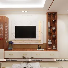 This living room design for a client in Bangalore features a custom TV unit that incorporates a puja mandir with traditional jali work. The unit blends white marble, warm wood, and brass accents for a modern yet culturally grounded feel.