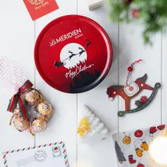 A flat lay of the 'Winter Wonderland' Christmas hamper contents, showcasing the branded tin, chocolates, and charming holiday-themed decorations.