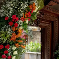A lush floral arrangement framing a traditional wooden doorway, blending vibrant colors with the rustic charm of the venue.