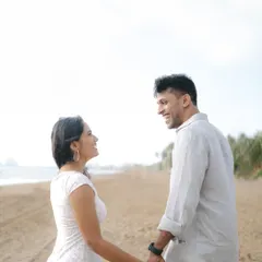A bright and airy photograph of a couple sharing a happy moment while walking hand-in-hand on the beach. This image captures the simple joy and effortless connection of a seaside pre-wedding shoot.