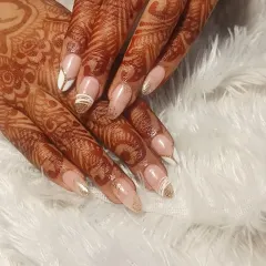 An elegant nail extension set designed for a bride. The design features a modern French look with white and gold glitter accents that beautifully complement the traditional henna.