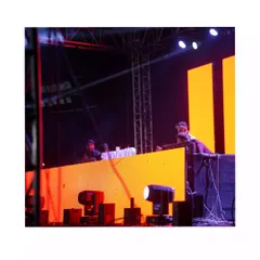 On the decks at a large outdoor festival. The stage setup with massive LED panels and lighting rigs is where I feel most at home, controlling the sound for a huge audience.