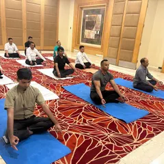 A corporate yoga session in progress at the Radisson Hotel in Noida. Participants are guided into a meditative state to help de-stress and recenter during a busy workday.