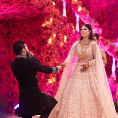 A truly magical proposal moment captured during an engagement ceremony. The groom is on one knee against a backdrop of vibrant red flowers, creating a dramatic and unforgettable image of this milestone.