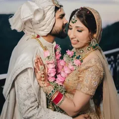 A tender moment between the couple against the backdrop of rolling green hills. The groom's gentle kiss on the bride's forehead captures the romance of their scenic wedding.