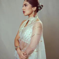 The side profile of this ivory saree look shows off the beautiful floral bun and statement earrings, proving that the back of an outfit is just as important as the front.