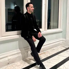 This relaxed pose showcases the tuxedo's sharp tailoring and how it maintains its silhouette, making it perfect for a sophisticated evening event.