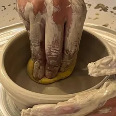 Using a sponge to smooth the inside of a freshly thrown bowl on the wheel. This step is crucial for refining the shape and ensuring a clean finish, a technique we teach in our pottery classes.