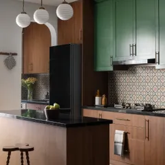 This kitchen was designed for both function and nostalgia. Bold green cabinets energize the space, while a vintage patterned backsplash is a nod to the kitchens the clients grew up in. The central island offers extra counter space without cluttering the room.
