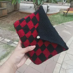 Holding my handmade checkerboard book sleeve. It's perfect for keeping your paperbacks safe in your bag. This red and black pattern is a fave, but I can make it in any color combo you want.