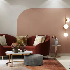 This living room uses a warm, analogous color scheme of blush pink and deep red to create a cozy and inviting atmosphere. The curved sofa and gold-accented lighting add a touch of modern elegance.