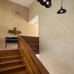 Another view of the stunning teak staircase, showing how it anchors the space. The warm wood tones are complemented by the earthy, textured finish of the walls and unique, artistic light fixtures.