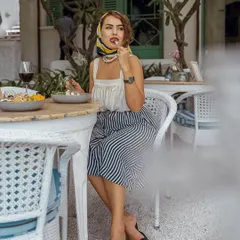A candid-style shot of a woman dining at Olive Bistro. The vintage-inspired styling with a headscarf and the action of eating create a narrative of enjoying 'la dolce vita'.