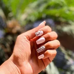A chic and graphic black and white design, with a mix of solid white nails and nails featuring a hand-drawn crosshatch pattern.