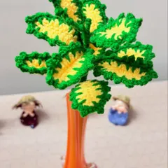 This crochet plant features bright green and yellow leaves, creating a cheerful and maintenance-free decorative piece.