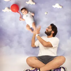Daddy, daddy cool! A fun and creative shot showing a proud father playing with his levitating baby, held up by a single red balloon.