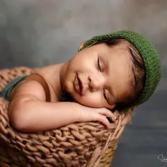 Look at that sweet smile! This little one is dreaming peacefully in a cozy basket. This shot was part of a sibling session, and he was so calm and happy.
