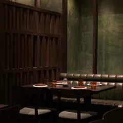Another view of the dining area at Otra. The combination of dark wood, green leather banquettes, and textured walls creates a rich, layered interior that feels both modern and timeless.