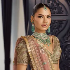 This is a classic Makeup by Pratiba bride. The look combines traditional elegance with a modern aesthetic, featuring soft glam makeup that complements the exquisite emerald and diamond jewelry.