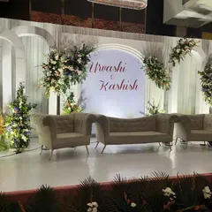 A closer view of a modern wedding stage with personalized details. The clean, arched backdrop provides a perfect canvas for the couple's names, framed by tasteful floral decor and stylish seating.