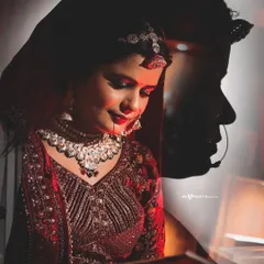 A creative double exposure portrait of the bride in her red wedding attire. Her thoughtful expression is layered with her silhouette, adding an artistic and emotional depth to the photograph.