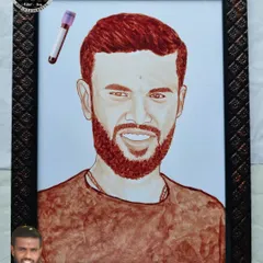 This image shows the finished blood portrait alongside a small photo of the artist, me, giving a sense of the person behind the art. The portrait itself is a striking likeness of the subject.