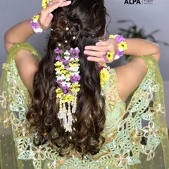 The final look of a handmade floral hairpiece adorning a messy bun. This is perfect for a vibrant Haldi ceremony.