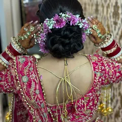 A detailed shot of a beautiful bridal bun adorned with fresh purple and white flowers. This showcases the hairstyling skills that complete the perfect bridal look.
