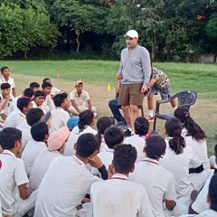 A wide view of a group mentorship session where trainees sit down with Virender Sehwag to discuss their progress and ask questions about the sport.