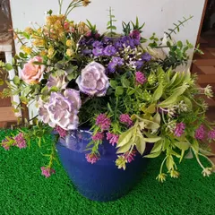 This bouquet showcases a mix of purple, pink, and yellow artificial flowers, creating a rich and textured look. Set in a blue ceramic pot, it’s a maintenance-free way to enjoy a garden-fresh feel indoors.