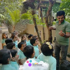 A guide at Discovery Village shows the children a flower, connecting them with nature and providing a real-world botany lesson.