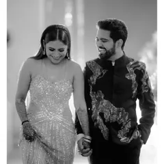The joy of walking together. This black and white candid shot captures the couple mid-laugh, holding hands as they move through their celebration, a perfect picture of shared happiness.