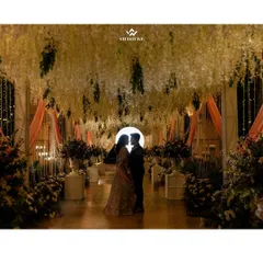 A breathtaking silhouette of the couple standing in a grand, beautifully lit floral archway at their reception. This shot is the epitome of romance and elegance.