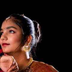 A classic profile shot that elegantly displays the traditional hairstyle and gold earrings. The dark background and focused lighting create a timeless and graceful portrait.