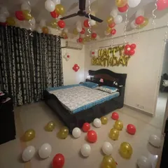 Even a simple decoration can make a big impact. This budget-friendly birthday setup includes red, white, and gold balloons on the ceiling and floor, with 'HAPPY BIRTHDAY' foil letters above the bed to create a festive mood.