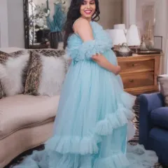 This light blue off-the-shoulder gown features soft ruffles and a long train. It's a perfect choice for an airy and feminine look, shown here in a comfortable indoor setting.