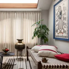 From the same AD India feature, this is the prayer room, lit by an expansive skylight. The space features a traditional Indian 'charpoy' daybed, Pichwai art, and antique brass artifacts.