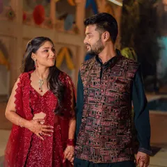 A full-length shot of the couple at their Sangeet. The bride is in a sparkling red lehenga and the groom in a stylish Indo-Western outfit, perfectly coordinated for the event.