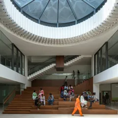 A full view of the multi-level staircase seating at Sona University, designed as an amphitheater-like space for social interaction. The large skylight above illuminates the area, making it a central point for student life and collaborative activities within the library block.