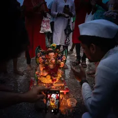 A devotee takes a photo of a small Ganesha idol before its immersion, a modern act of reverence within an ancient tradition.