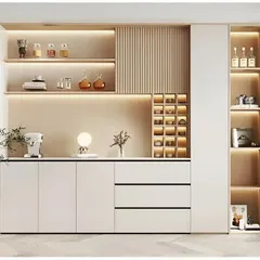 This minimalist and bright crockery unit in white and light wood offers a variety of storage options. It includes open shelves with backlighting, a small wine rack, drawers, and a vertical display cabinet.