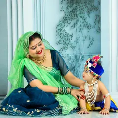 Another beautiful moment from our Janmashtami session. The mother, dressed in a lovely green and blue outfit, lovingly gazes at her son in his adorable Krishna costume, creating a cherished memory of this cultural celebration.