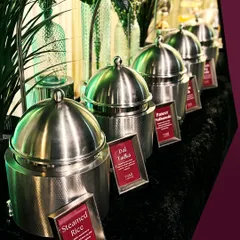 A lineup of our classic Indian main courses, including Steamed Rice, Dal Tadka, and Paneer Highlands. Each dish is served in modern stainless steel chafing dishes with clear labels.