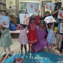 Look at these proud smiles. After a story about friendship and kindness, the children hold up their beautiful handprint art, a wonderful reminder of the day's theme.