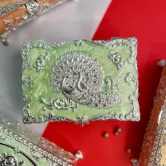 This charming enamel box in a soft pastel green is adorned with a silver peacock and floral details. It is perfect for storing jewelry, keepsakes, or any small treasures.