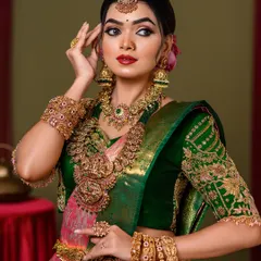 A classic pose showcasing the intricate details of a South Indian bridal look. The makeup features a sharp, defined eye, a bold lip, and a flawless base that glows.