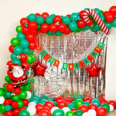 I created this classic Christmas photo booth with a shimmering silver foil curtain and a red and green balloon frame. It includes fun elements like a candy cane balloon and a 'Merry Christmas' banner for memorable party pictures.