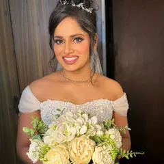 A happy bride, holding her bouquet. The makeup is designed to be flawless and long-lasting, ensuring she looks perfect in every photo.