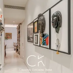 Another view of the art-filled hallway, showcasing a collection of framed masks and paintings. This gallery-like experience draws the eye and adds a layer of personality and culture to the home's design.